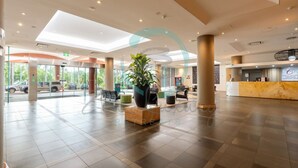 A spacious lobby with a reception desk, seating area, and a large potted plant. - Rustic Sunset Horizon Oceanview Balcony Dining (Darwin)