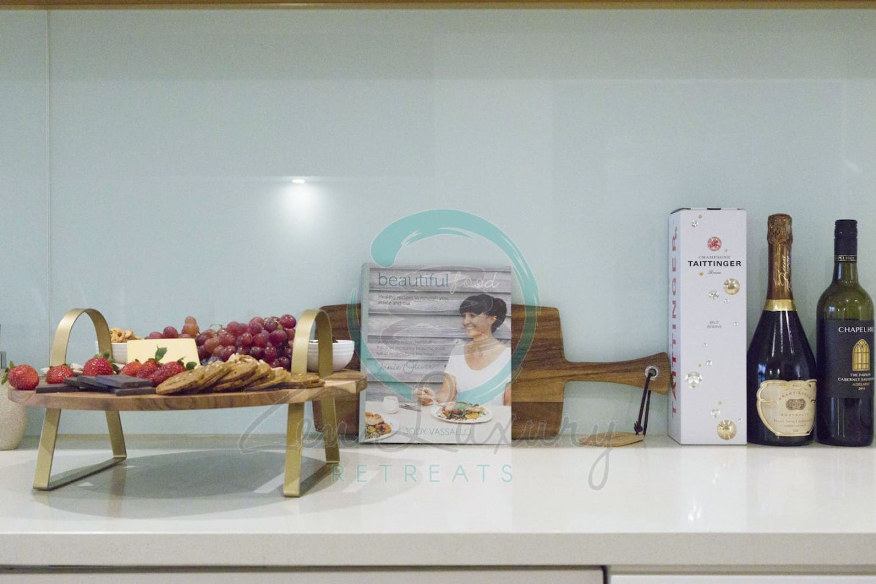A table with a wooden board holding snacks and a bottle of wine.