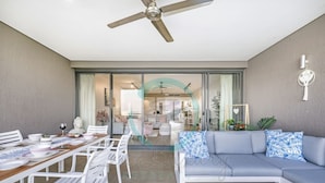 Ein modernes Wohnzimmer mit Sofa, Esstisch, Stühlen und Deckenventilator.