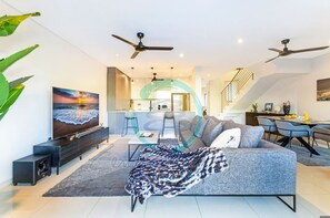Un salon moderne avec un canapé, un téléviseur et des ventilateurs de plafond.