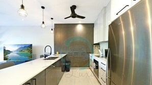 Egy modern konyha rozsdamentes acél hűtőszekrénnyel, fehér munkalappal és függesztett lámpákkal.