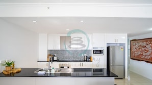 A modern kitchen with white cabinets, a black countertop, and stainless steel appliances. - Zen Mitchell Rooftop Outdoor Dining Oceanview (Darwin)