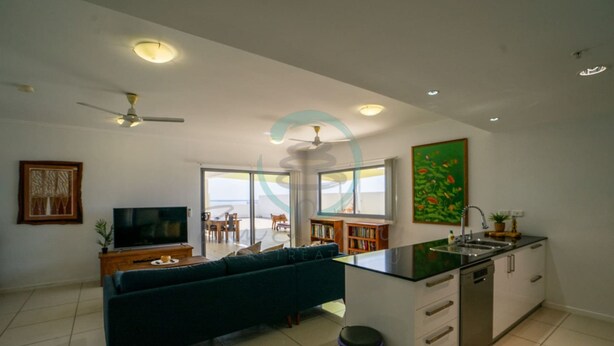 A modern living room with a sofa, TV, and a dining area with chairs and a table. - Zen Mitchell Rooftop Outdoor Dining Oceanview (Darwin)