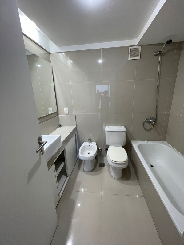 A modern bathroom with a toilet, bidet, sink, and bathtub.