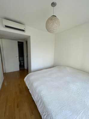 Ein Schlafzimmer mit einem großen Bett, Holzboden, Deckenventilator und Klimaanlage.