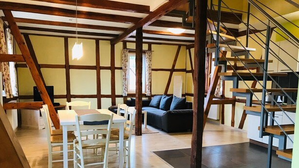 Un salón amplio con una mesa de comedor y sillas, un sofá y una escalera.