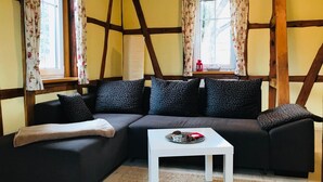 Una sala acogedora con un sofá oscuro, una mesa de centro blanca y cortinas estampadas.