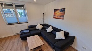 Ein modernes Wohnzimmer mit einem Ecksofa, einem Holztisch und einem Gemälde an der Wand.