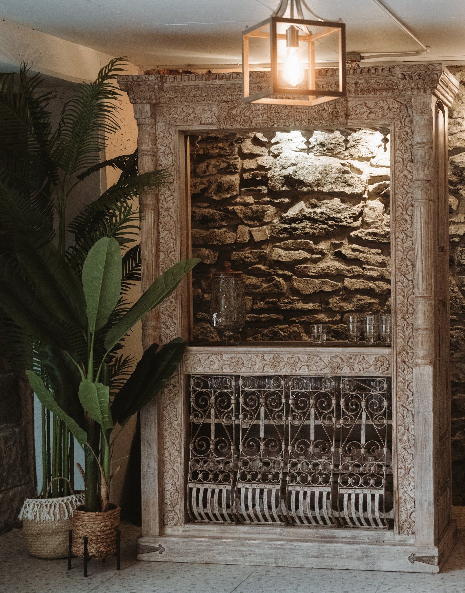 A stone wall with a decorative metal grill and a hanging light fixture.