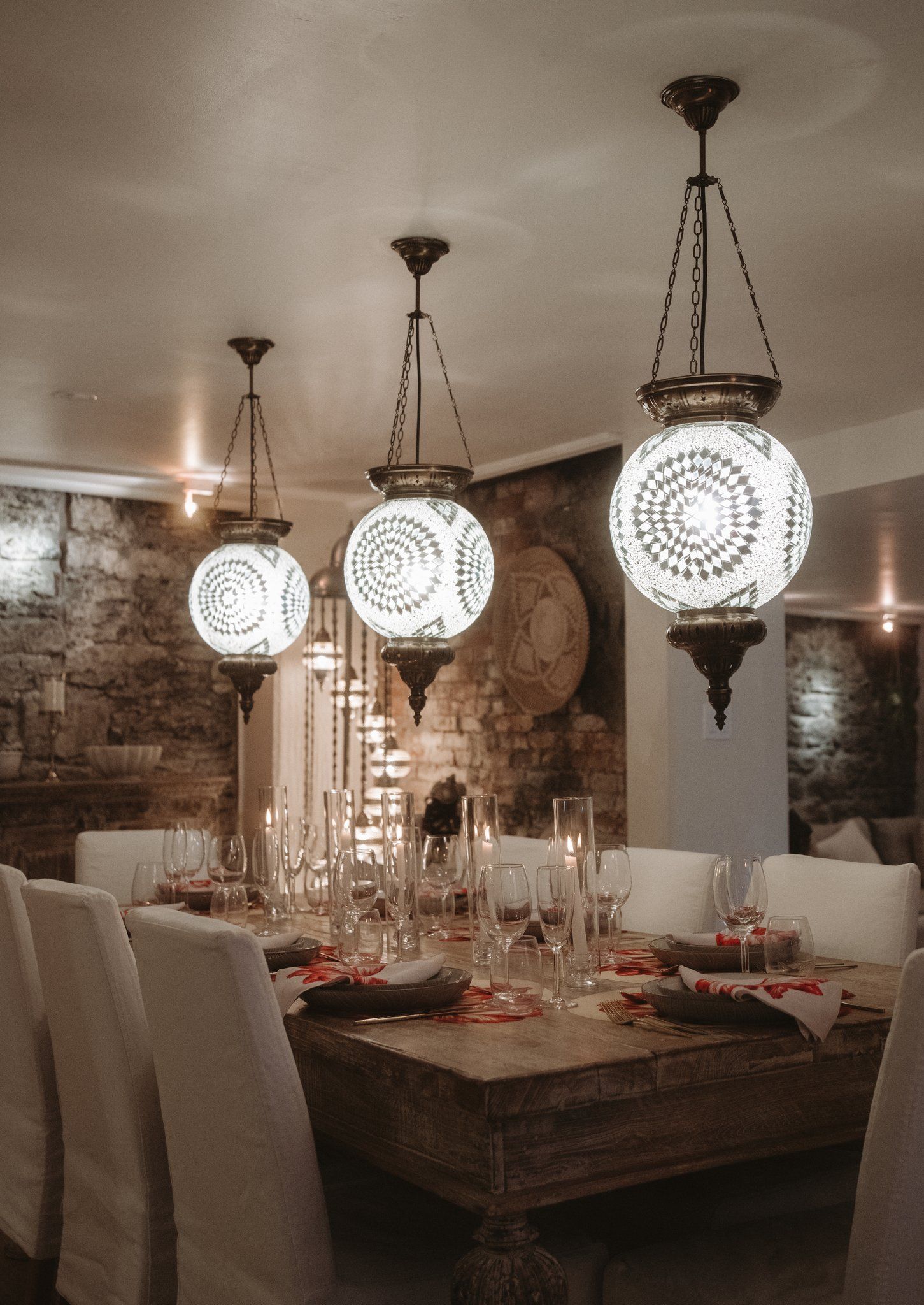 A dining area with a wooden table set for a meal, surrounded by chairs.