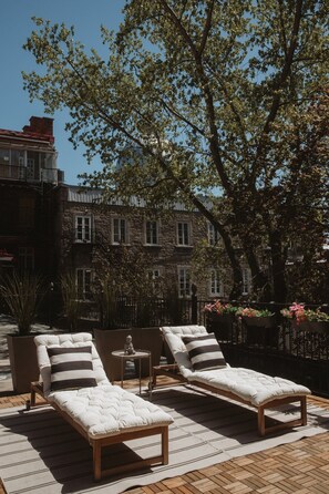 Una terraza en la azotea con dos sillones de relax, una mesita y una estatua.