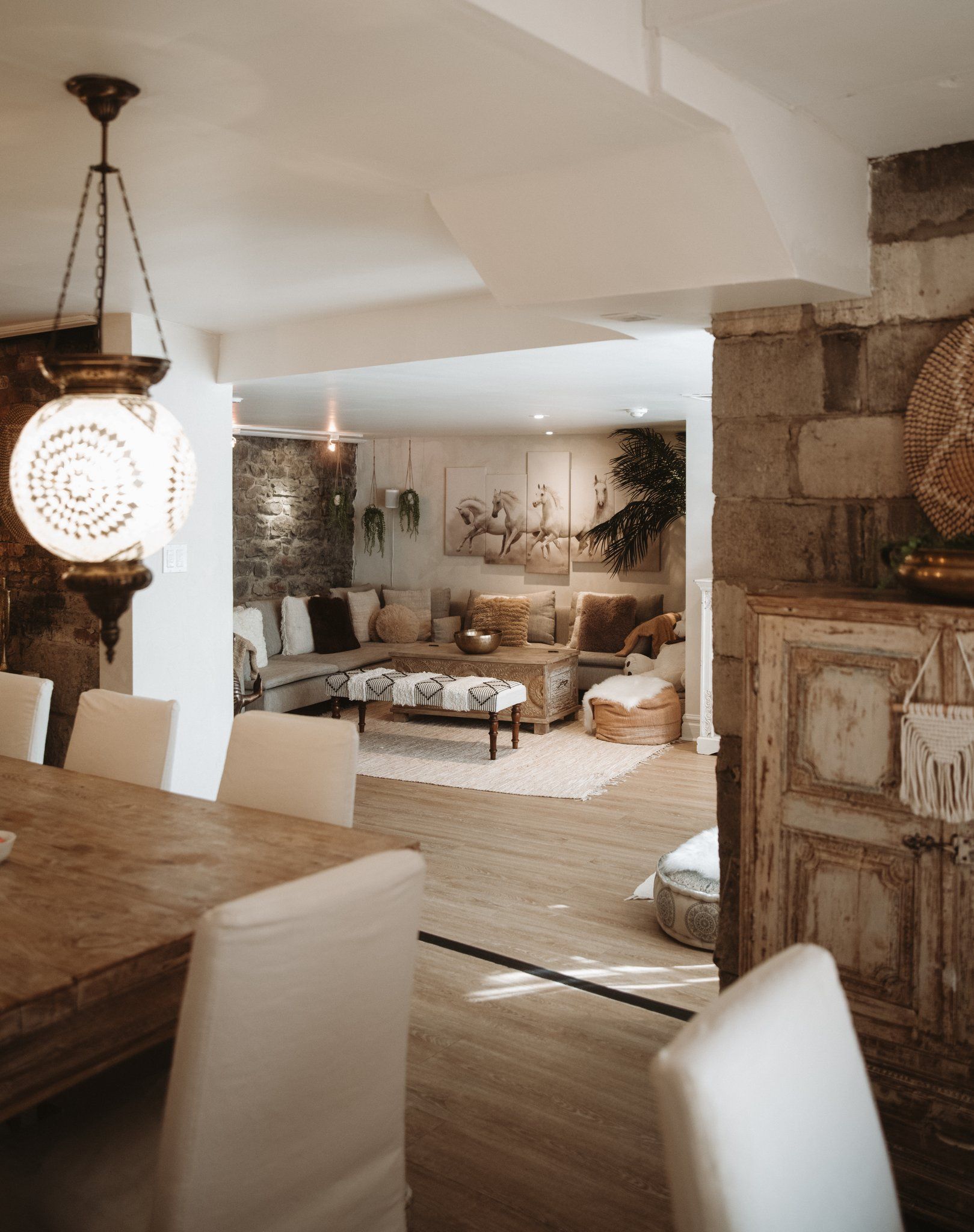 A cozy living room with a stone wall, a wooden dining table, and a hanging light fixture.