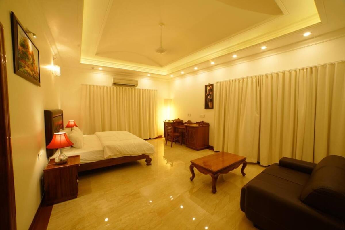 A hotel room with a bed, a desk, a chair, a sofa, and a coffee table.