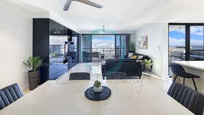 Ein modernes Wohnzimmer mit Essbereich, Deckenventilator und Blick auf die Stadt durch große Fenster.