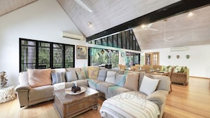 Un salon spacieux avec un plafond haut, une grande fenêtre et un plancher en bois.
