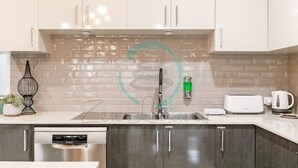 A modern kitchen with white cabinets, a stainless steel dishwasher, a built-in oven, and a tiled backsplash. - Zenhouse Stylish Lawn Workspace Outdoordining (Muirhead)
