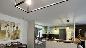 Eine moderne Küche mit einer zentralen Kochinsel, einem Essbereich mit Holztisch und einem Wohnbereich mit Sofa.