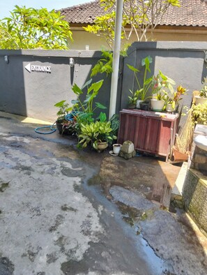 Una entrada cerrada con un letrero, plantas en macetas y suelo de concreto.