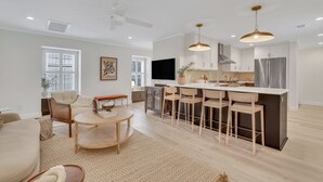 Una cocina moderna con una isla central, taburetes de bar y una mesa de comedor.