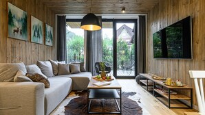 A modern living room with a sofa, coffee table, and a large TV mounted on the wall.