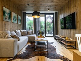 Una sala de estar moderna con un sofá, una mesa de centro y un televisor grande montado en la pared.