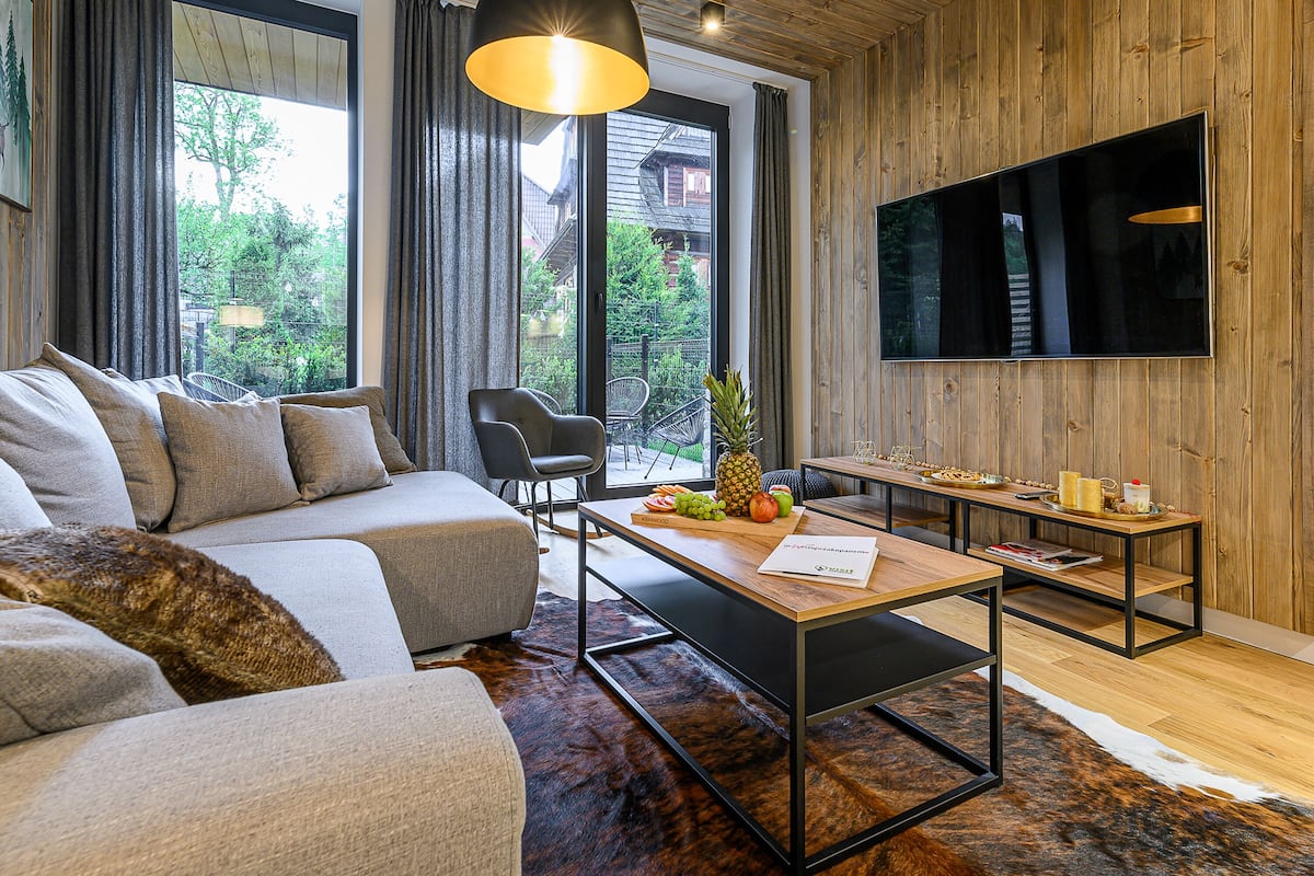 A modern living room with a sofa, a coffee table, a TV, and a wooden floor.