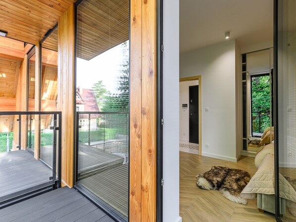 A modern interior with a wooden balcony, a pet-friendly area, and a view of the outdoors.