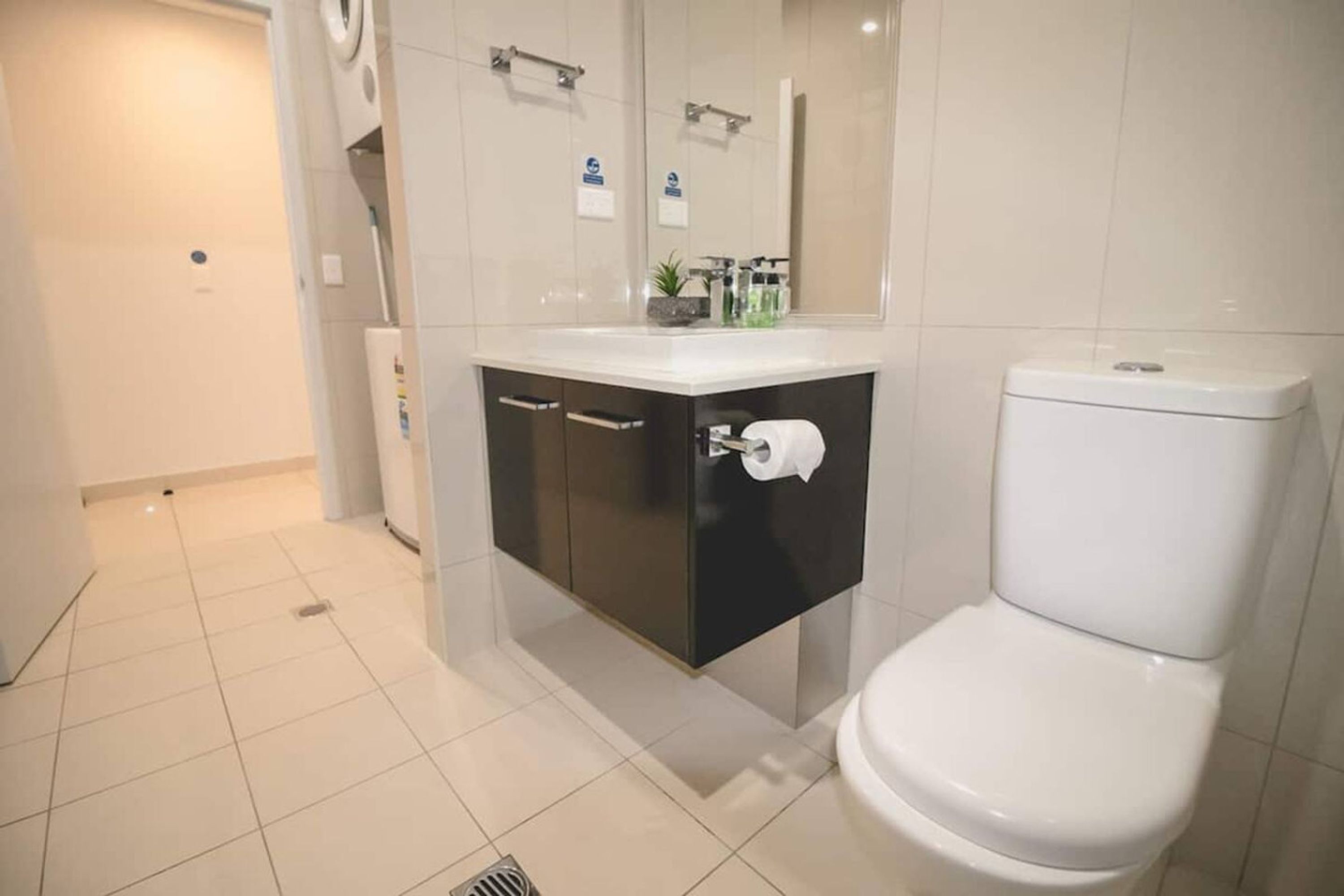 A modern bathroom with a toilet, a sink with a mirror, and a shower area.
