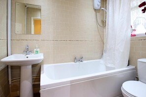 Une salle de bain avec une baignoire blanche, un lavabo et des toilettes.