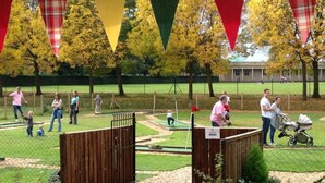 Un parc doté d’un terrain d’entraînement au putting, d’un pont en bois et d’une zone délimitée par une clôture.