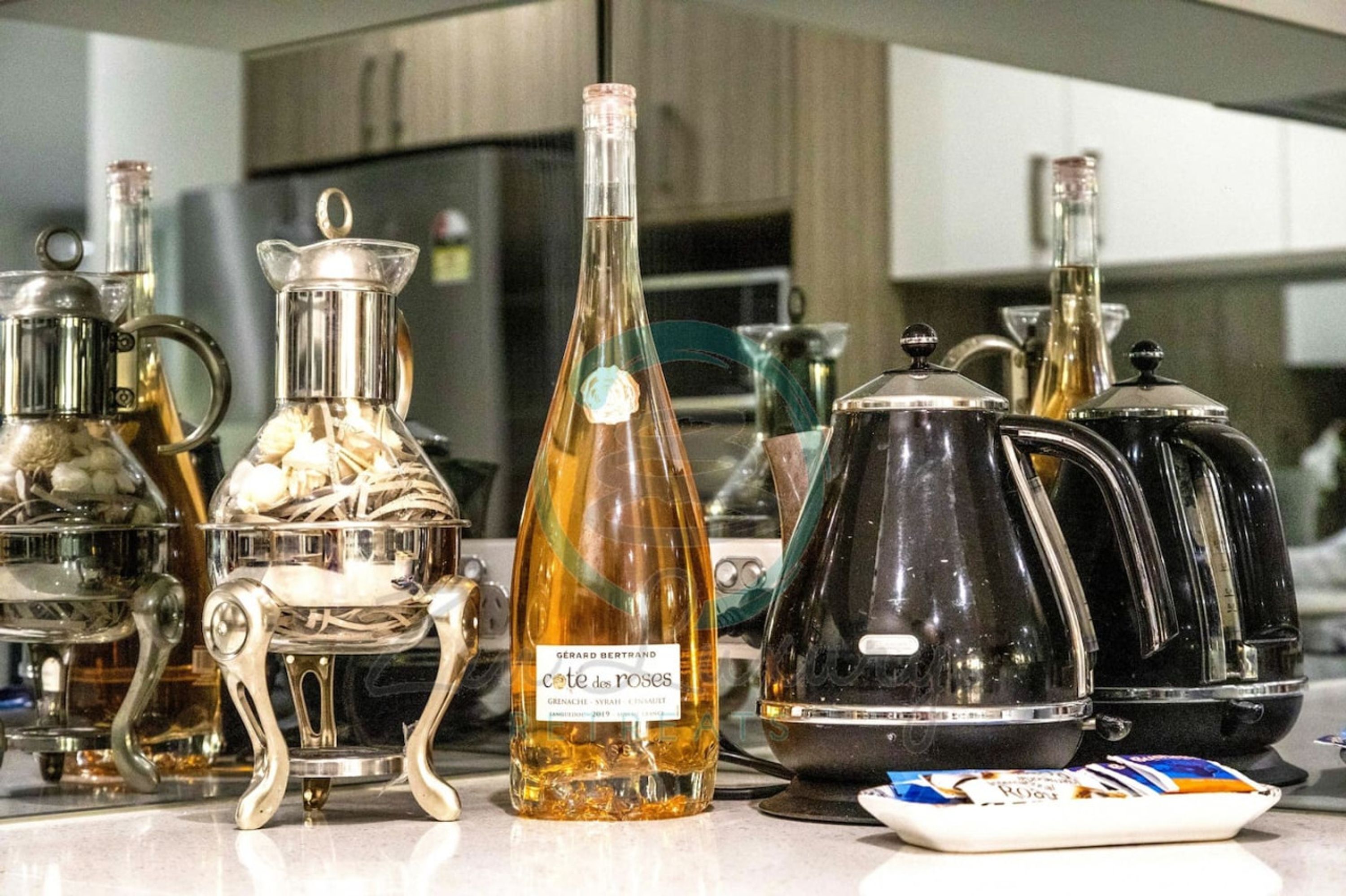 A kitchen with various glassware and bottles, including a bottle labeled "cote des roses".
