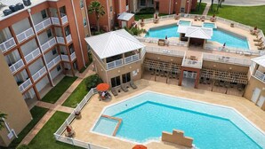 Um hotel com uma grande piscina exterior, várias varandas e zonas de estar ao ar livre.