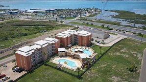 Um hotel com vários edifícios, piscina e vista para o oceano.