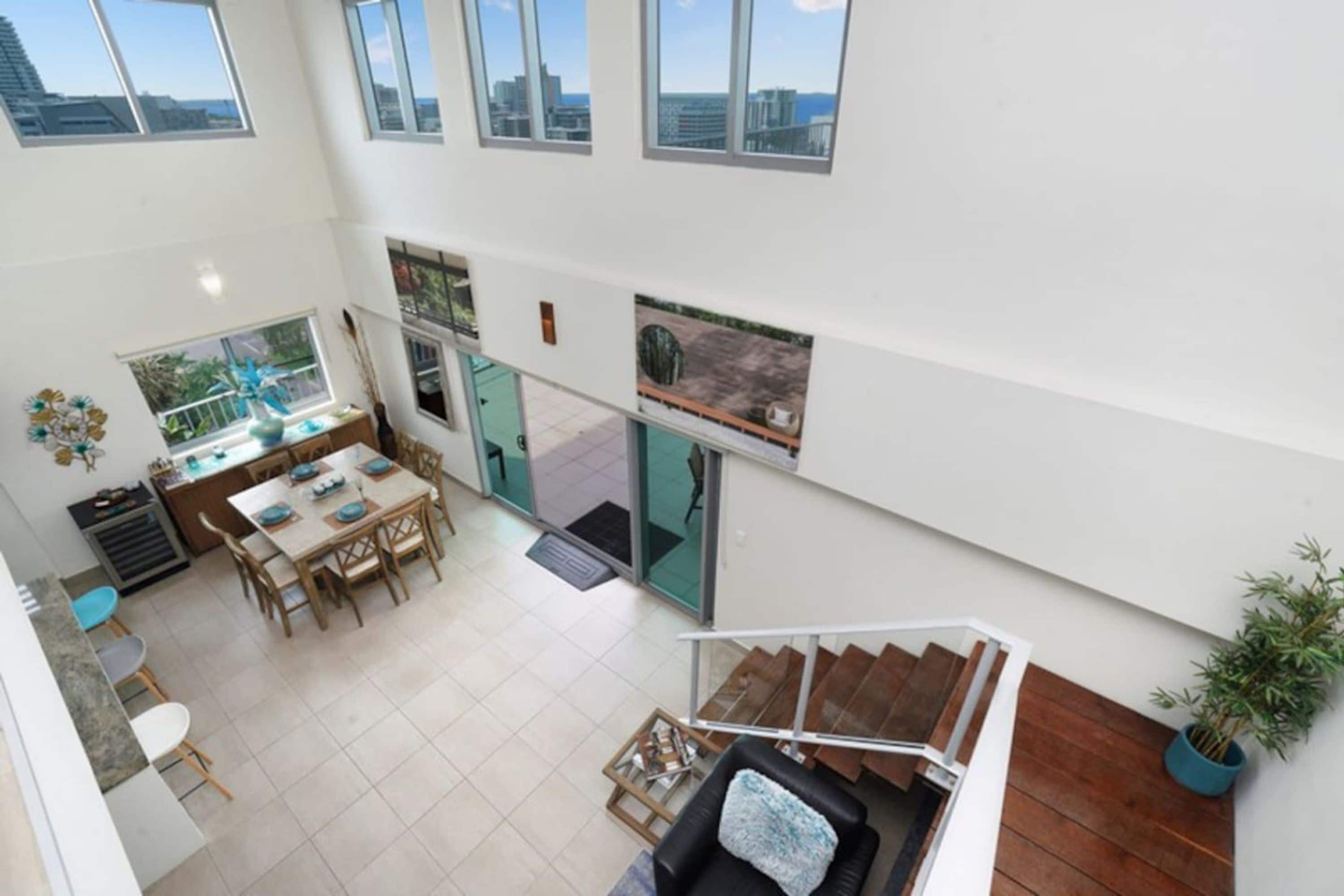 A spacious interior with a dining area, kitchen, and a staircase leading to an upper level.
