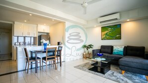 A modern living room with a sofa, coffee table, and a dining area with chairs and a table. - Zen Ocean Pebble 1-br 1-ba Sea View Retreat (Darwin)