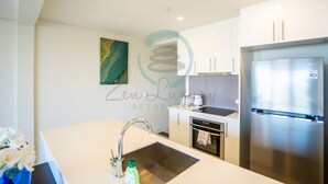 A modern kitchen with stainless steel appliances, a white countertop, and a single burner stove. - Zen Ocean Pebble 1-br 1-ba Sea View Retreat (Darwin)
