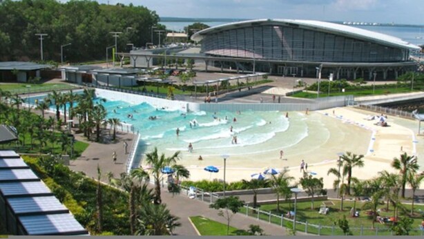 A large swimming pool with a beach area, a covered spectator area, and a view of the ocean. - Zen Ocean Pebble 1-br 1-ba Sea View Retreat (Darwin)
