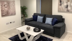 A modern living room with a grey sofa, white coffee table, and artwork on the walls. - Stunning 1 Bedroom Apartment in Bicester Town (Bicester)