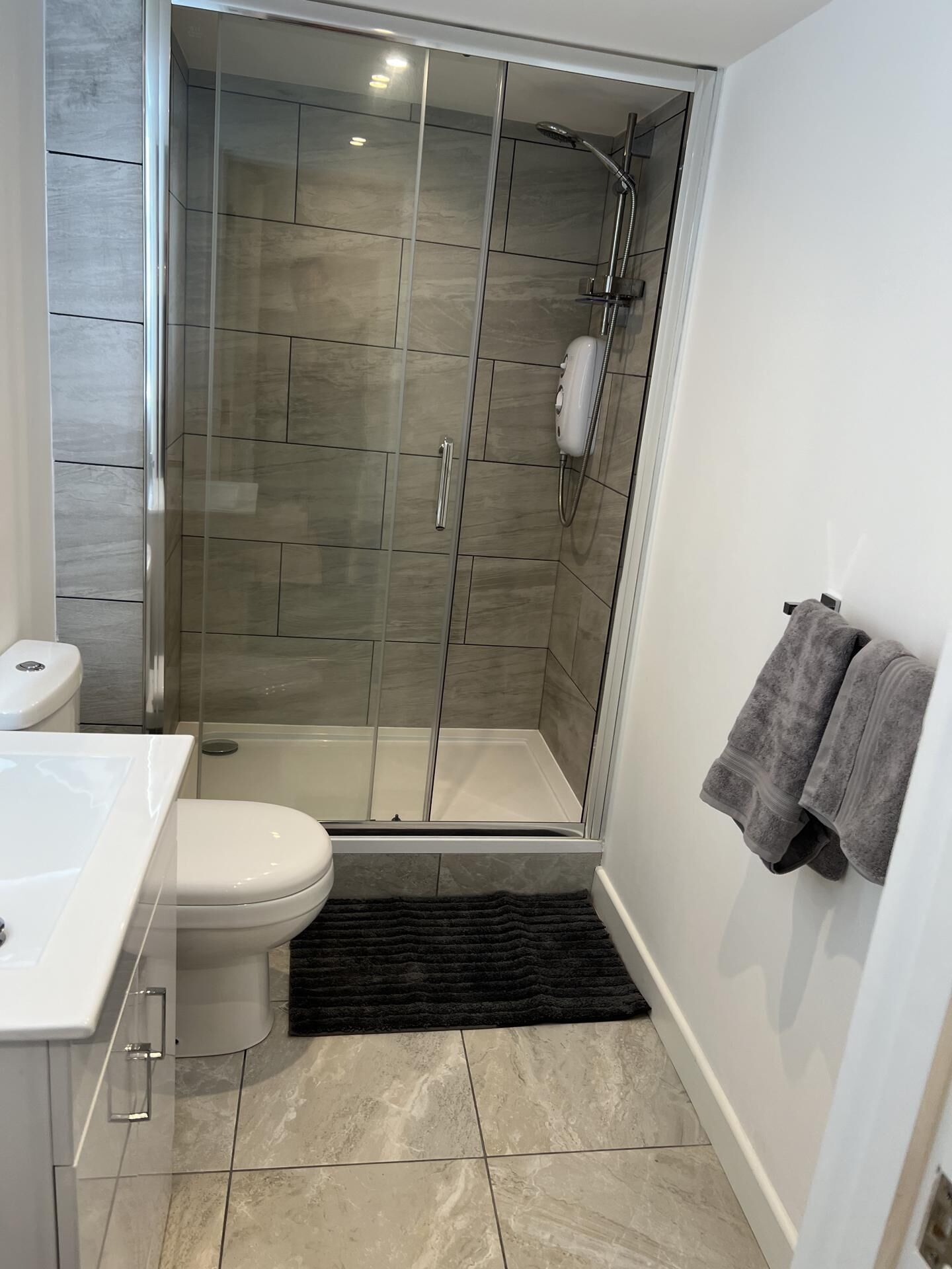 Une salle de bain moderne avec une douche à parois de verre, des toilettes et un lavabo.