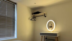 A bedroom with a bed, a bedside table with a mirror, and a window with blinds. - Stunning 1 Bedroom Apartment in Bicester Town (Bicester)