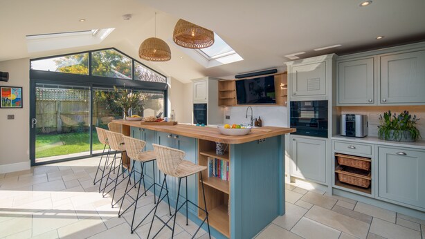 A modern kitchen with a central island, bar stools, and a view of the garden through large sliding doors. - The Beach House - sleeps 8 guests  in 4 bedrooms (Bembridge)