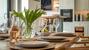 A dining table set with plates, glasses, and a vase with flowers. - The Beach House - sleeps 8 guests  in 4 bedrooms (Bembridge)