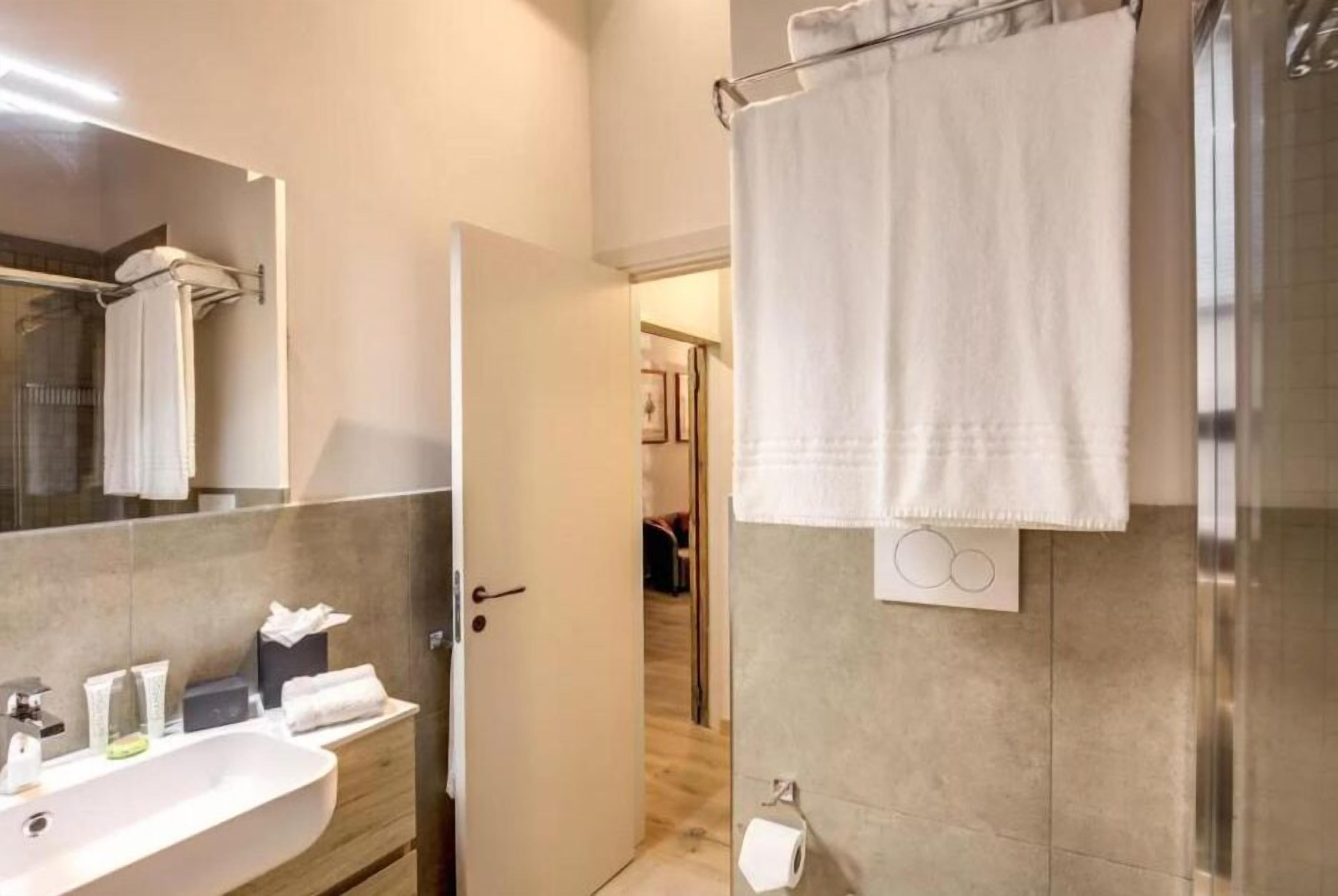 Une salle de bain moderne avec un grand miroir, un lavabo et un espace douche.