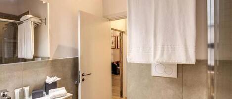 Une salle de bain moderne avec un grand miroir, un lavabo et un espace douche.