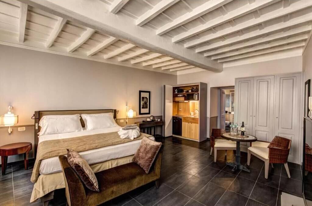 A hotel room with a large bed, a small table, and a kitchenette.
