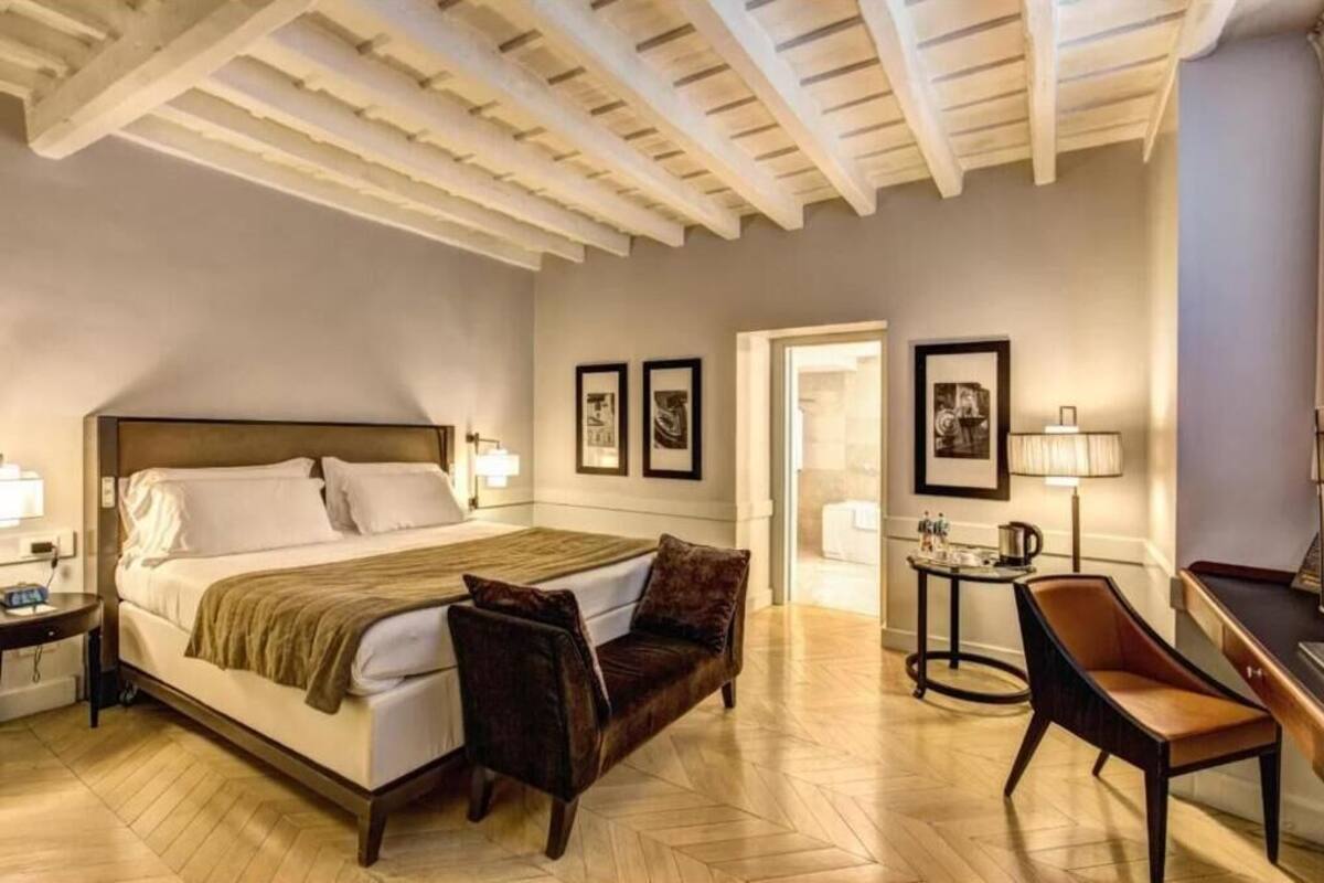 A hotel room with a bed, a desk, a chair, and a lamp.