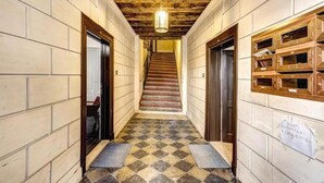 A hallway with a checkered floor, wooden walls, and a staircase leading to another floor.