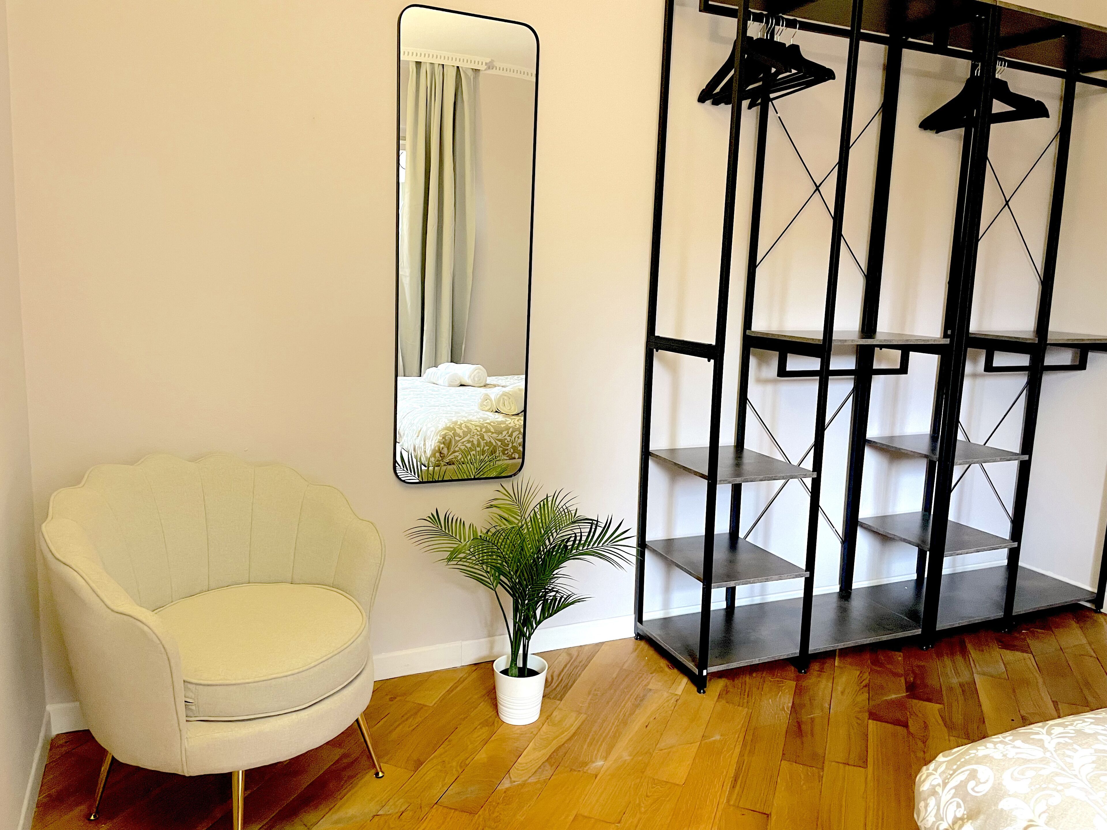 Een kamer met een spiegelkast, een stoel, een potplant en een bed.