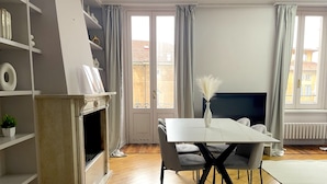 A modern living room with a white dining table, grey chairs, and a fireplace. - Best View Boutique Apartments  (Bergamo)
