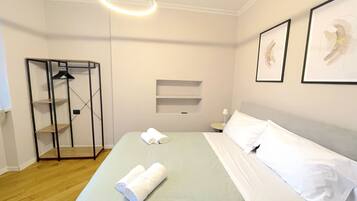 A hotel room with a bed, a wardrobe, a hanging light fixture, and two framed pictures on the wall.